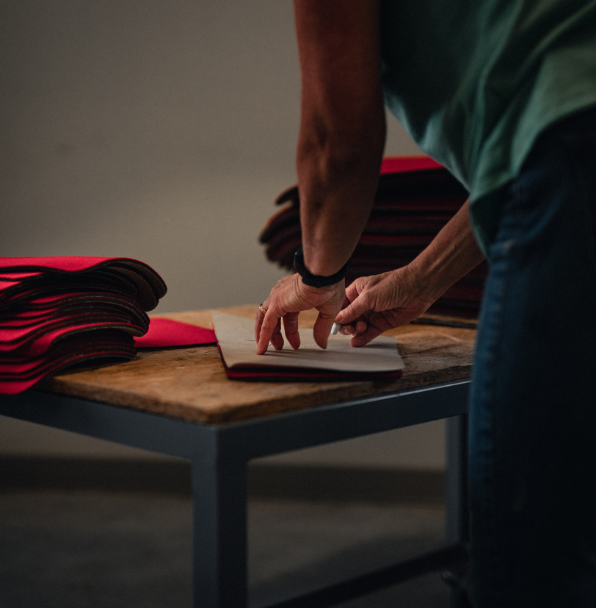 Personne pliant du carton sur une table en bois.