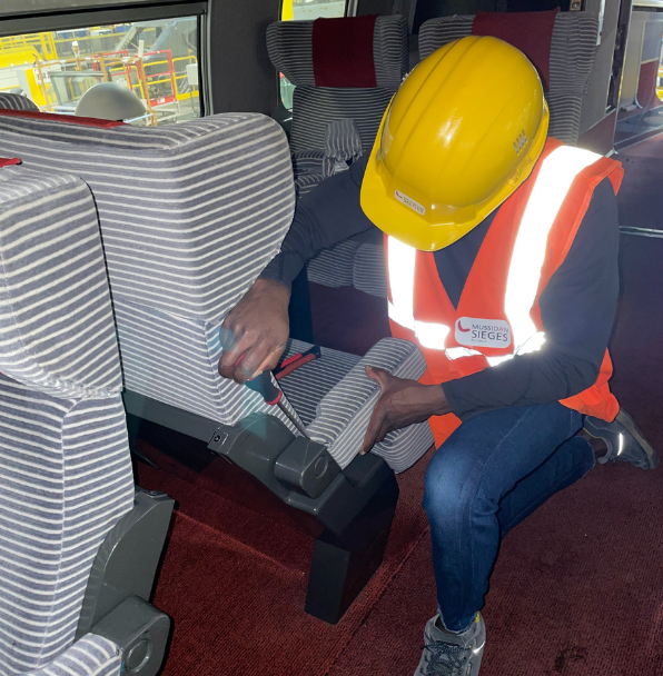 Technicien réparant un siège de train, avec casque