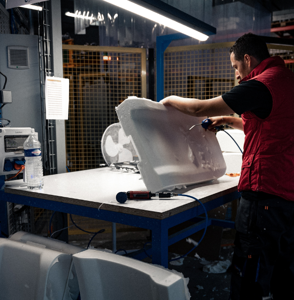 Homme découpant mousse blanche avec outil électrique.